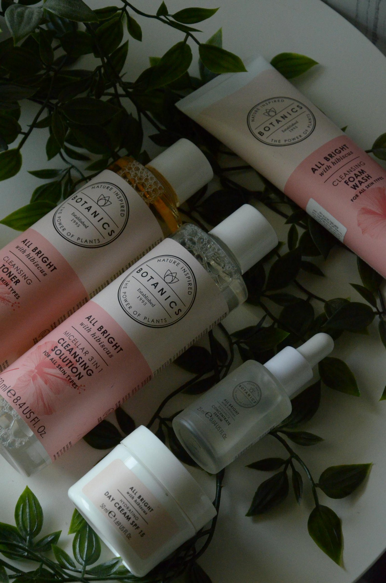 A stylish flat lay of skincare products surrounded by fresh greenery, ideal for beauty and wellness themes.